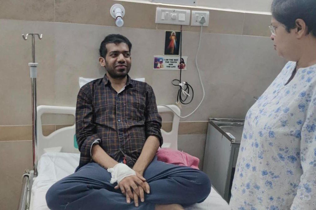 Ashley smiling, sitting cross-legged on his hospital bed