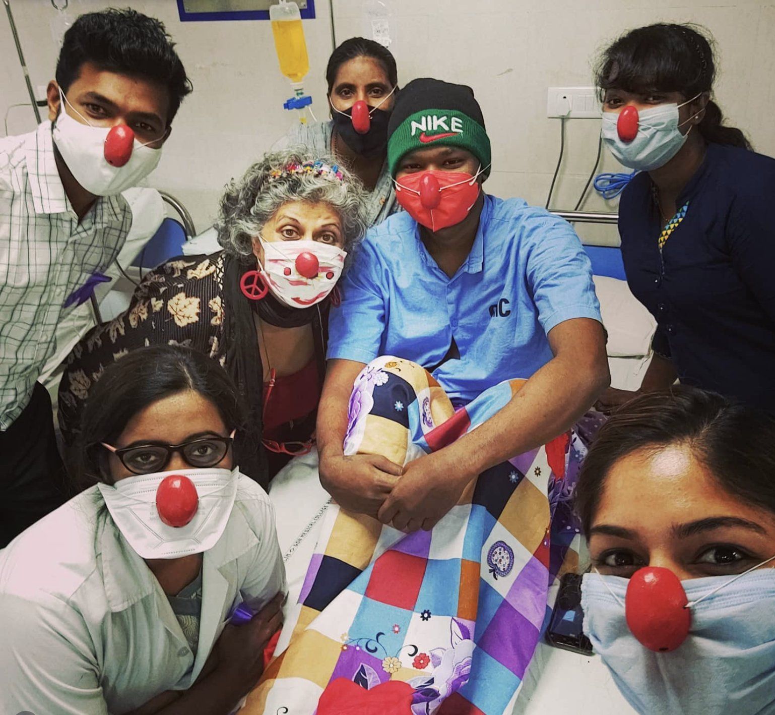 Sabrcare volunteers in red clown noses keeping a young patient company on the ward