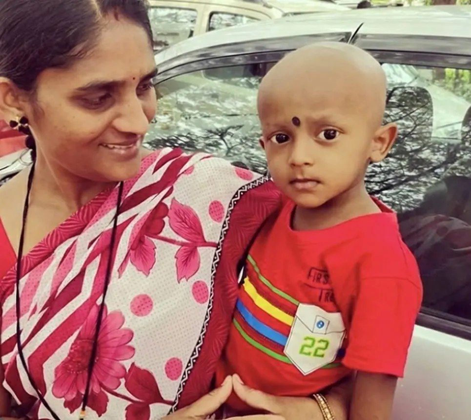 A smiling mother holding her young son in a red T-shirt