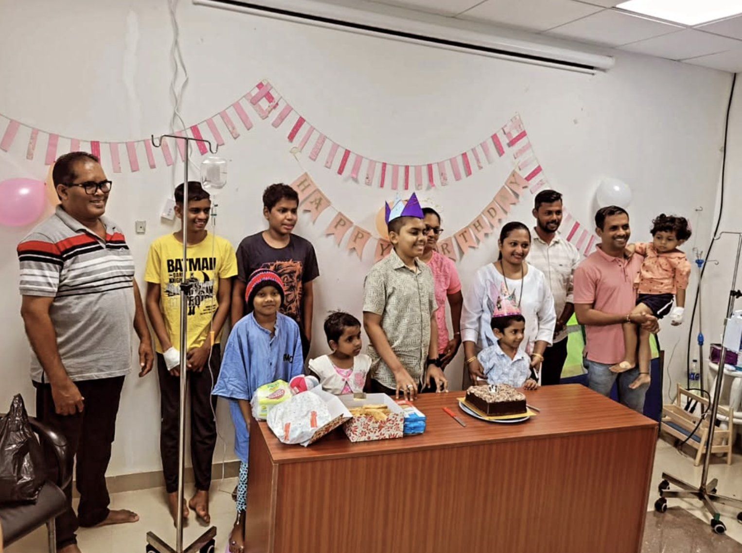 Children and families celebrating a birthday with cake on the oncology ward